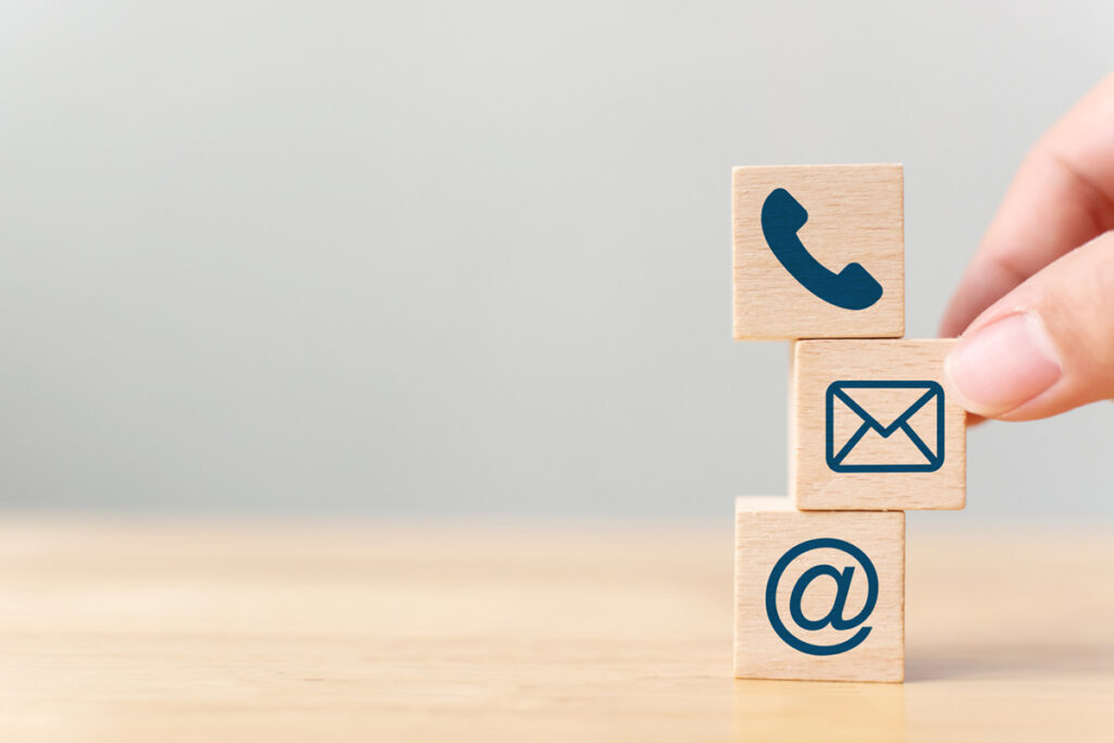 Hand putting wooden block cube symbol telephone, email, address. Website page contact us or e-mail marketing concept