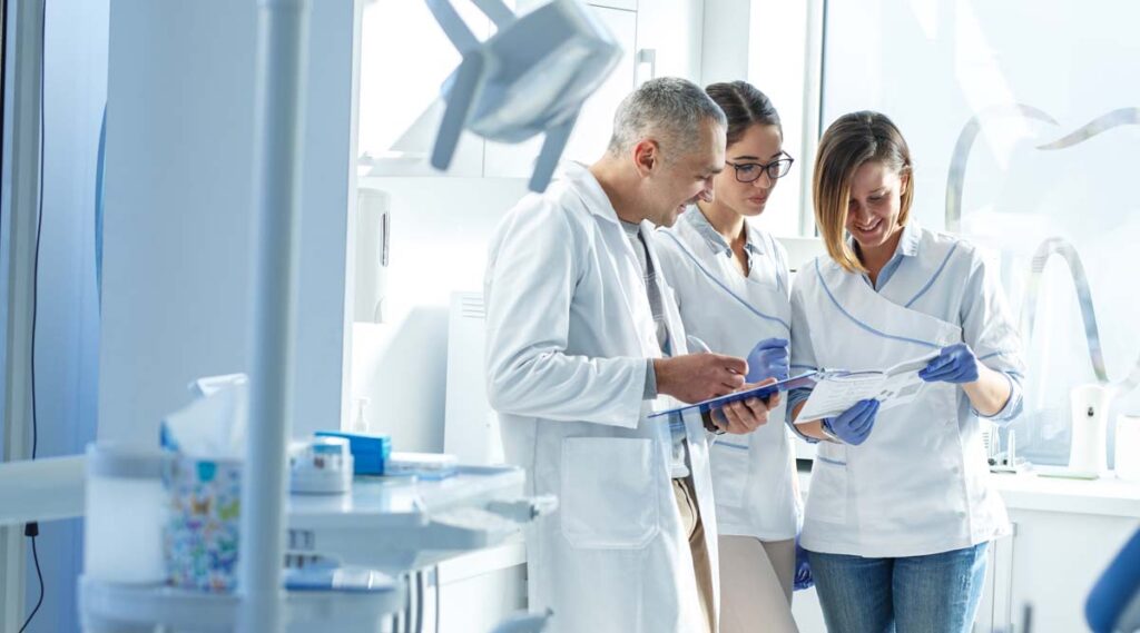 Ein Zahnarzt stimmt sich im Zuge der Mitarbeiterf&uuml;hrung mit seinem Team ab.