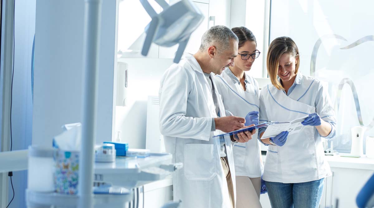 Ein Zahnarzt stimmt sich im Zuge der Mitarbeiterführung mit seinem Team ab.